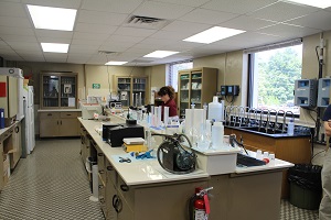 the water testing lab, with staff checking a fluid mix inside a glass beaker