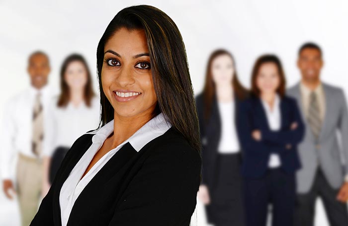 Minority woman in business suit, with blurred images of other people and minorities in business wear standing in background