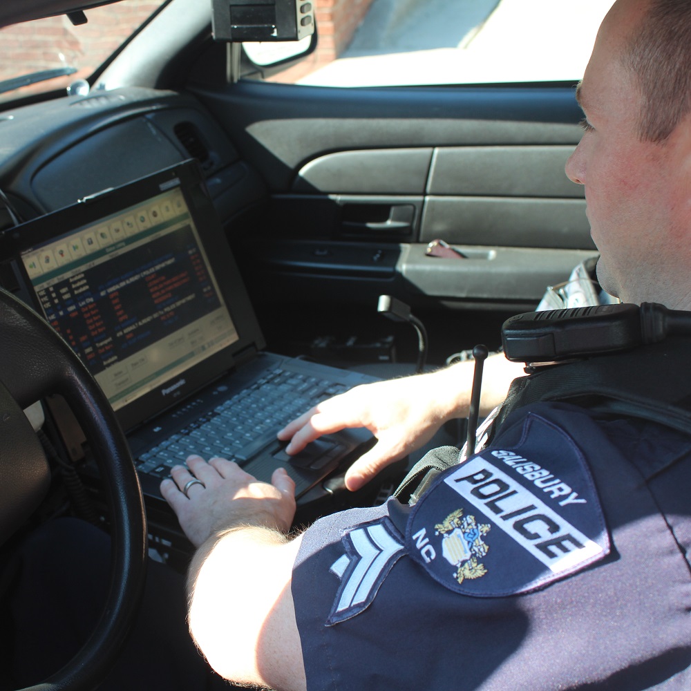 A male officer checking his computer inside his patrol car
